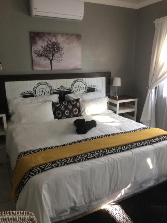 una camera da letto con un grande letto bianco con un cappello sopra di B&B 464 on 22nd Ave a Pretoria