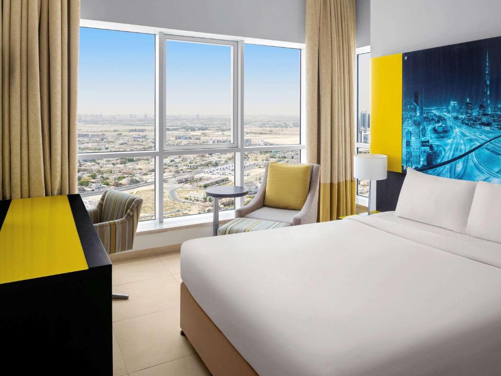 a hotel room with a bed and a large window at Adagio Premium Dubai Al Barsha in Dubai