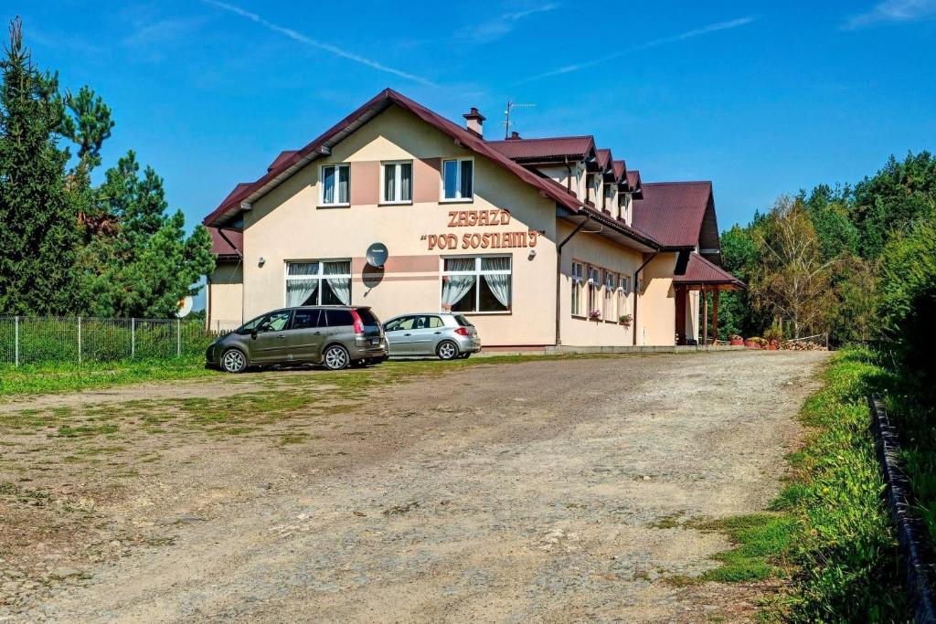 a building with two cars parked in front of it at Zajazd pod Sosnami in Berezka