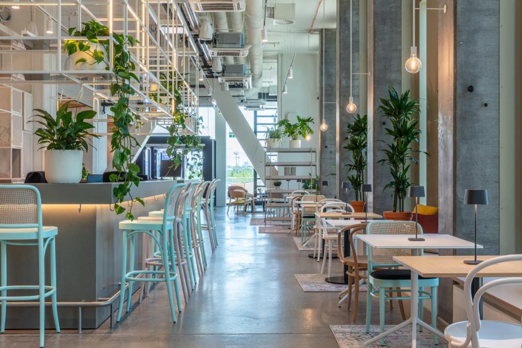 un restaurante con mesas, sillas y plantas en District Living en Viena