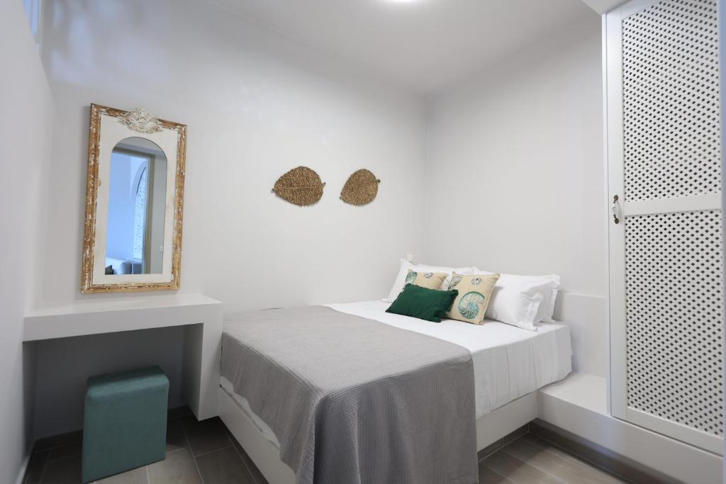 a white bedroom with a bed and a mirror at Captain's Pounda Suite in Apróvaton