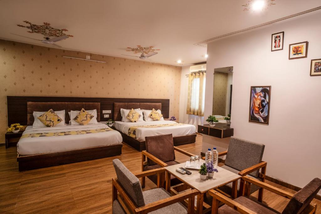 ein Hotelzimmer mit 2 Betten, einem Tisch und Stühlen in der Unterkunft Tripli Hotels Arunoday Palace in Udaipur