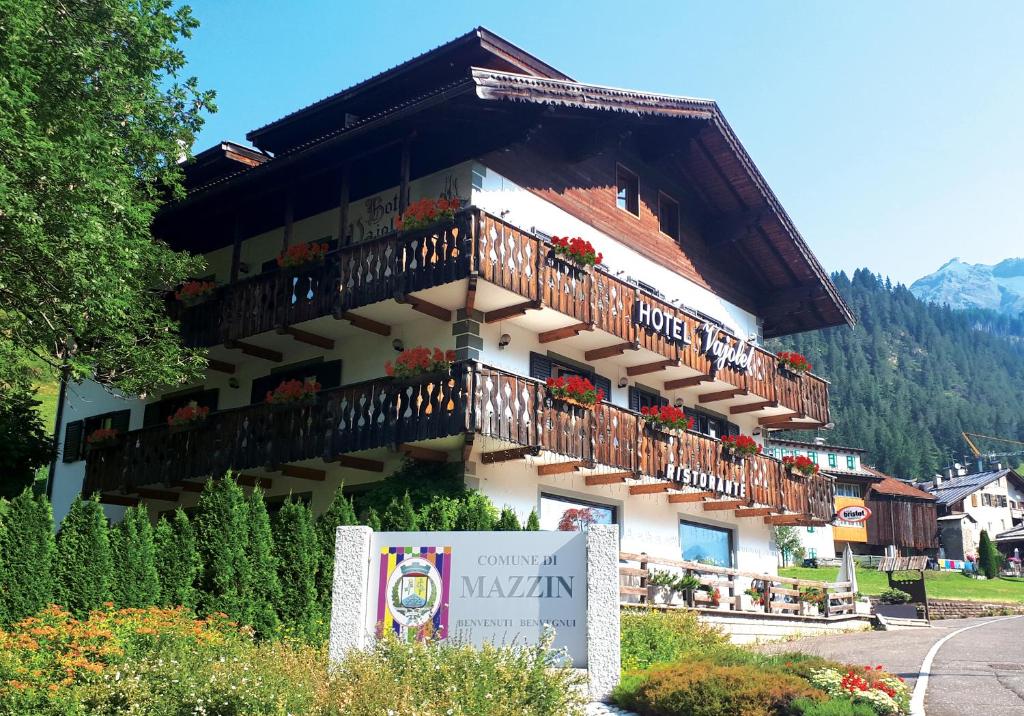 un edificio con balconi e un cartello di fronte ad esso di Hotel Vajolet a Mazzin