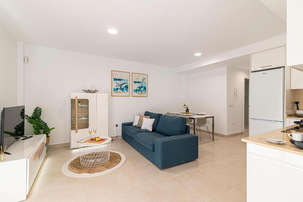 uma sala de estar com um sofá azul e uma cozinha em Edf BRISA en El Médano em El Médano