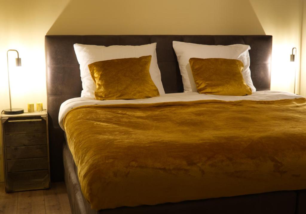 een slaapkamer met een groot bed met 2 gele kussens bij Bed and Breakfast Hans en Gridje in Breda