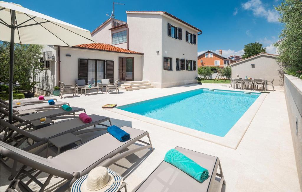 a villa with a swimming pool and patio furniture at Awesome Apartment In Medulin With Outdoor Swimming Pool in Medulin