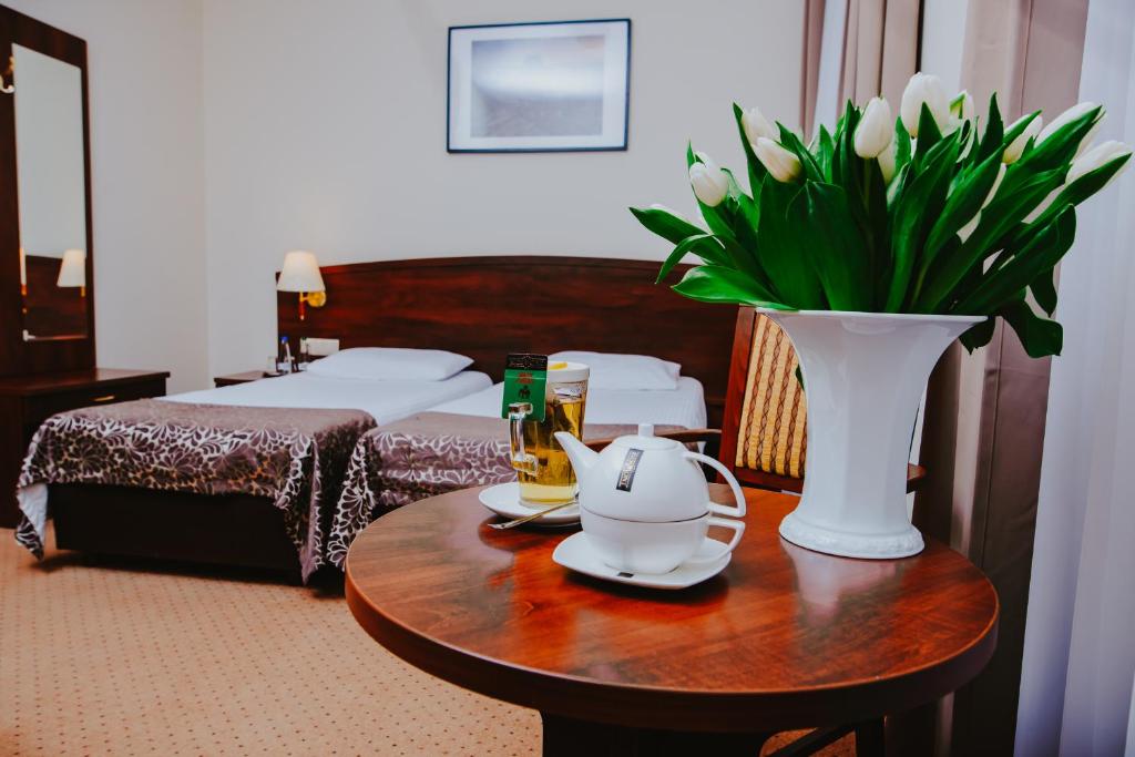 um quarto de hotel com uma mesa com um vaso de flores em Hotel Korel em Poznań
