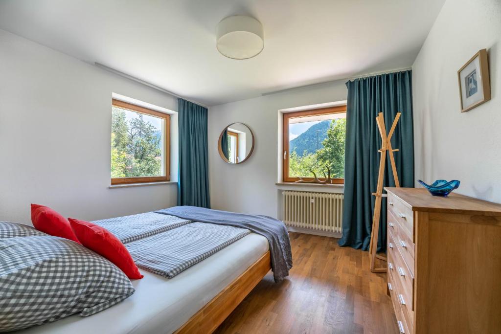 ein Schlafzimmer mit einem Bett, einer Kommode und zwei Fenstern in der Unterkunft Alpenraum in Bad Hindelang