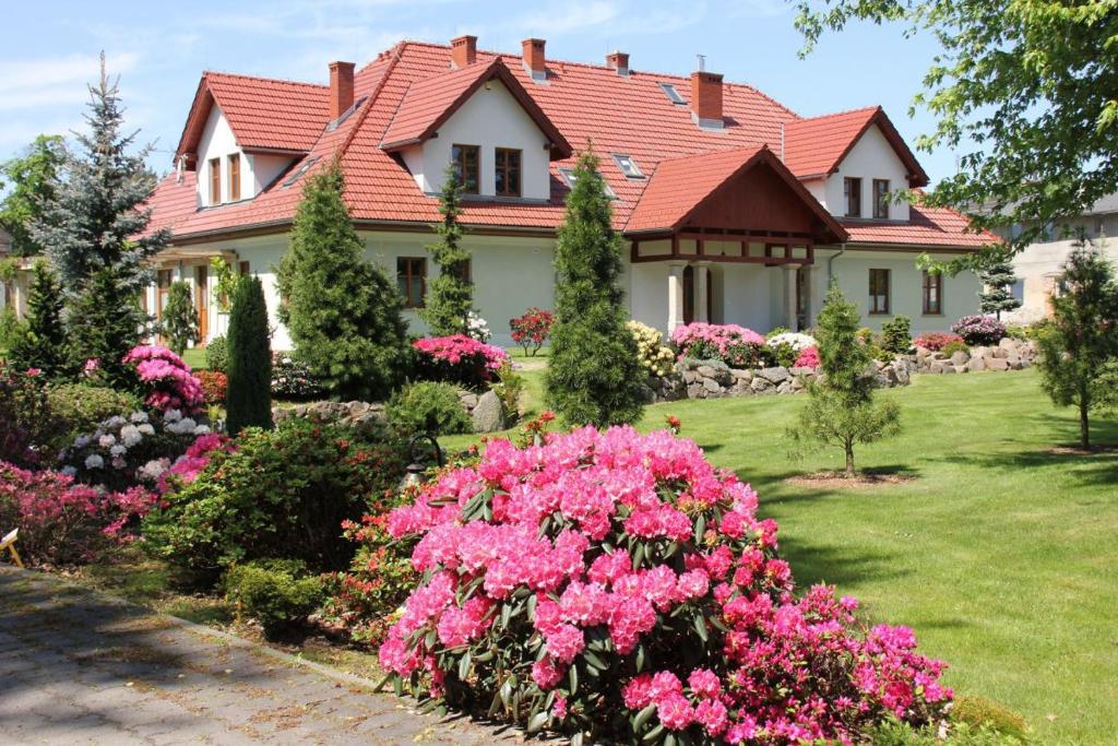 uma casa com flores cor-de-rosa no quintal em Dworek Azalia em Iłowa