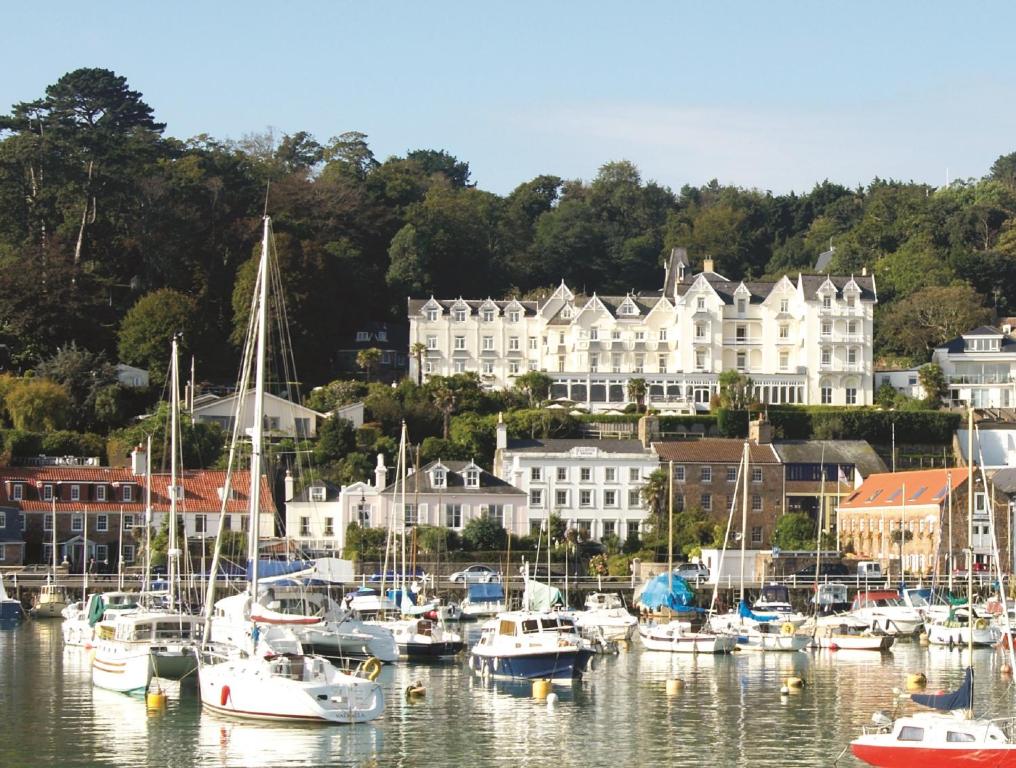 un gruppo di imbarcazioni ormeggiate in un porto con edifici di Somerville Hotel a Saint Aubin