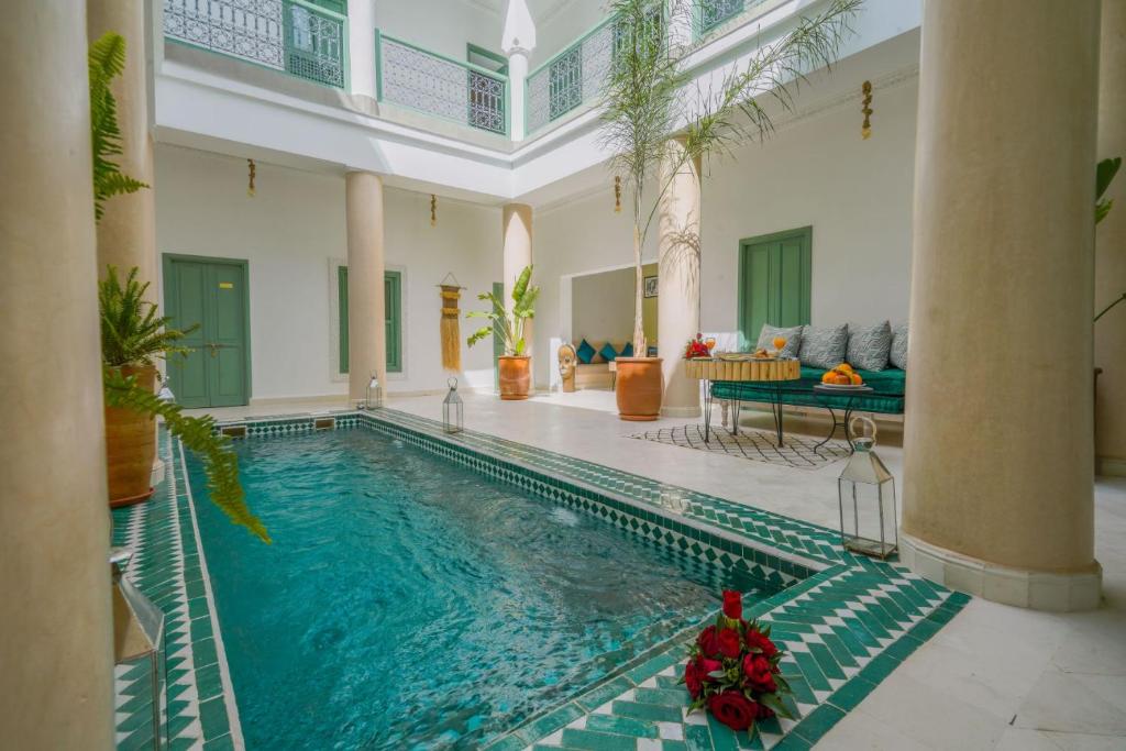 een groot zwembad in een kamer met een huis bij Riad Trésor Marrakech in Marrakesh