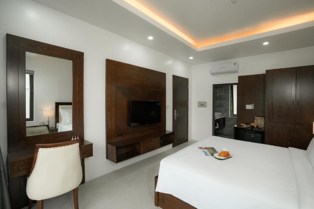 a bedroom with a white bed and a mirror at DAD Resort Phú Quốc in Phú Quốc