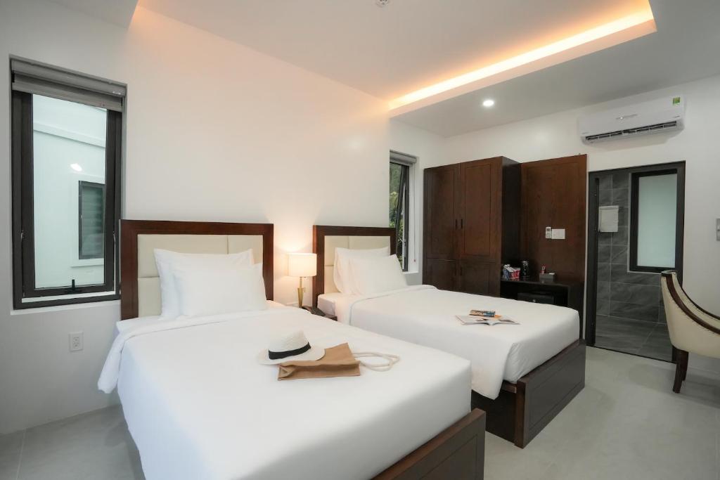 two beds in a hotel room with a hat on top at DAD Resort Phú Quốc in Phú Quốc
