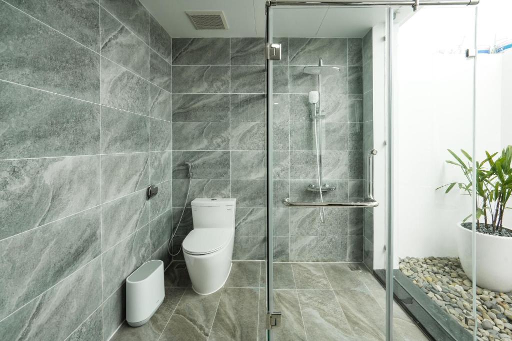 a bathroom with a toilet and a glass shower at DAD Resort Phú Quốc in Phú Quốc