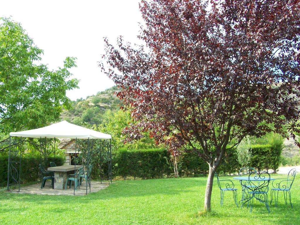 una mesa, sillas y una sombrilla en un patio en Apartamentos Casa Esperanza - Ordesa, en Laspuña