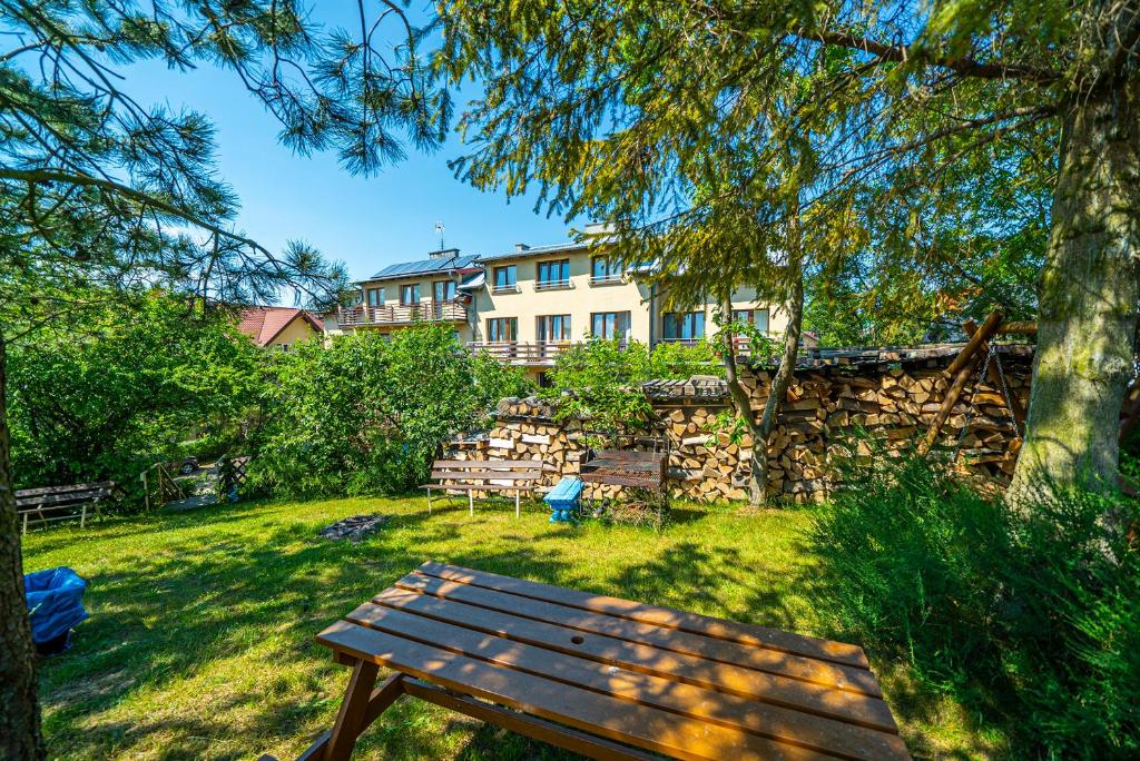 a wooden bench in a yard with a building in the background at Arka Przystań in Jastrzębia Góra