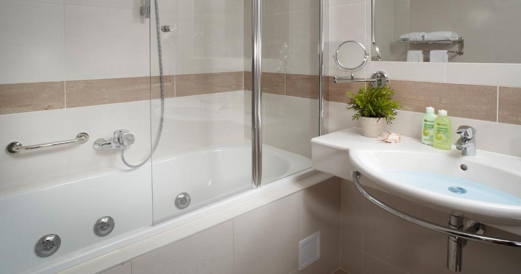 a white bathroom with a shower and a sink at Clarion Congress Hotel České Budějovice in České Budějovice
