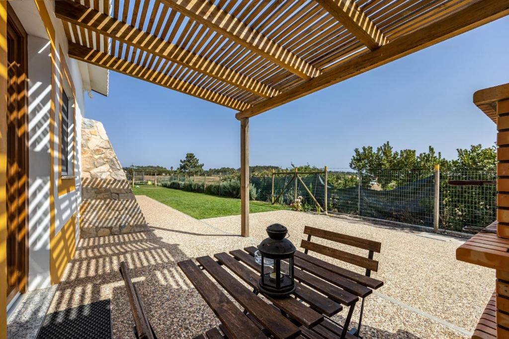 a wooden bench sitting under a wooden pergola at Monte do Tanoeiro - Casa Nova in Rogil