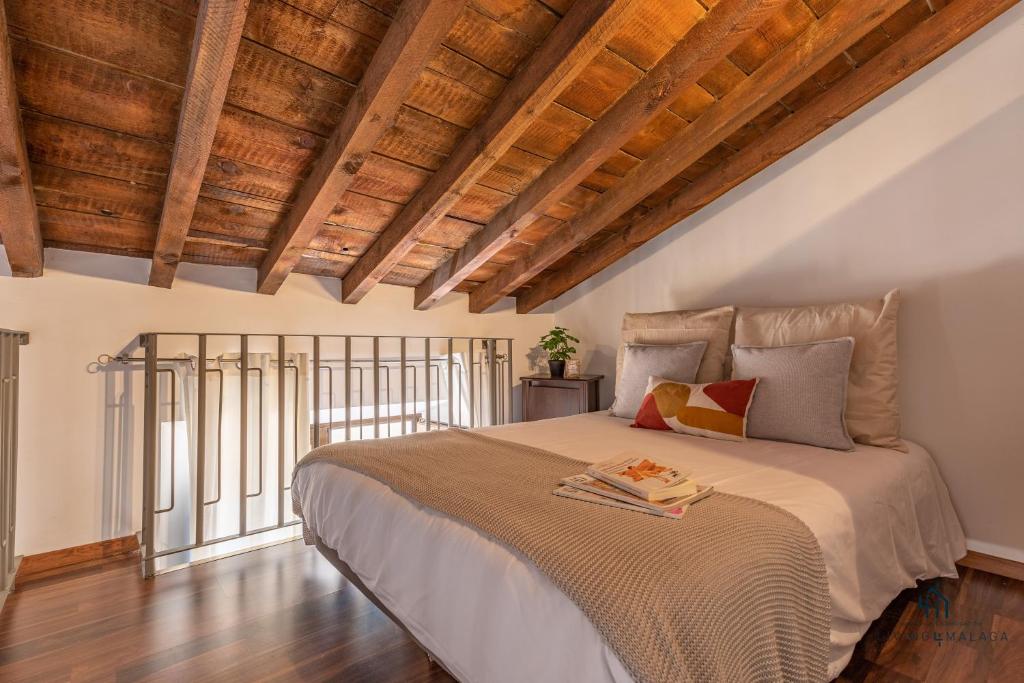 um quarto com uma cama grande e tectos em madeira em Living4Malaga La Dolce Vita Duplex em Málaga