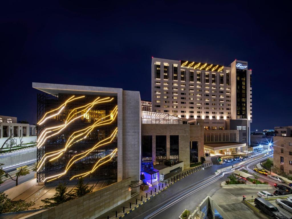 a building with lights on the side of it at night at Fairmont Amman in Amman