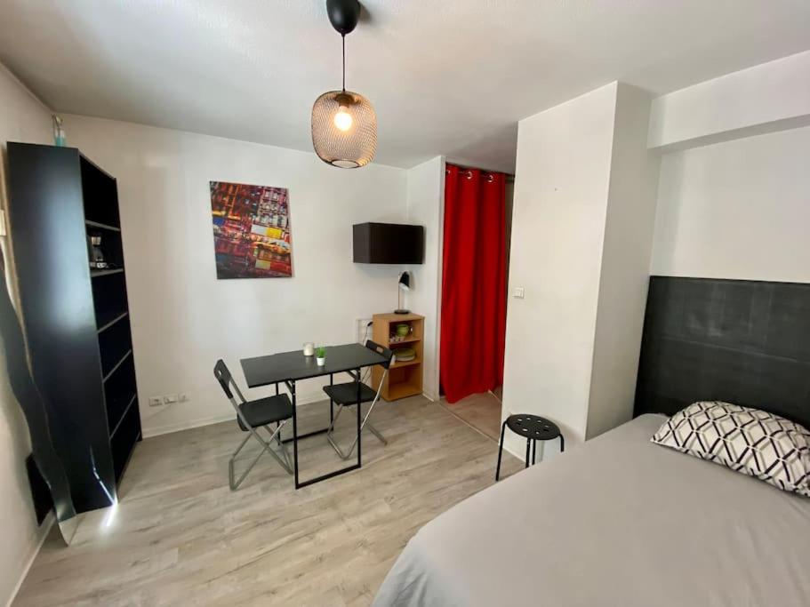 a bedroom with a bed and a desk with chairs at Studio le République in Dijon