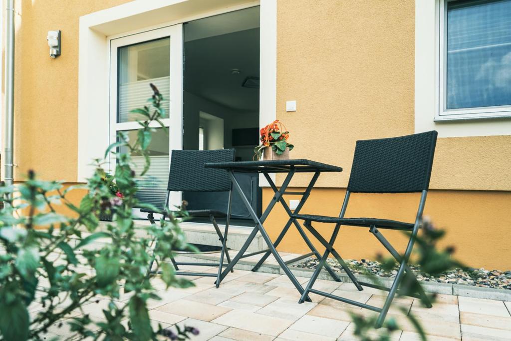 deux chaises et une table devant une maison dans l'établissement Apartment Haus Inge, à Dürrröhrsdorf
