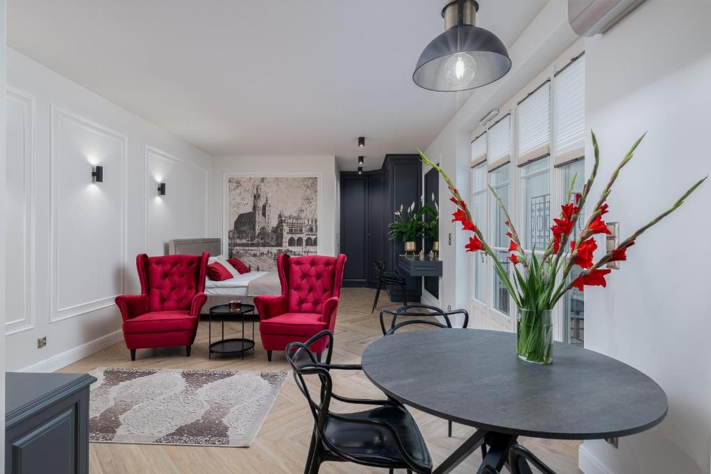 uma sala de estar com cadeiras vermelhas e uma mesa com um vaso de flores em Apartament w centrum Krakowa 109 em Cracóvia