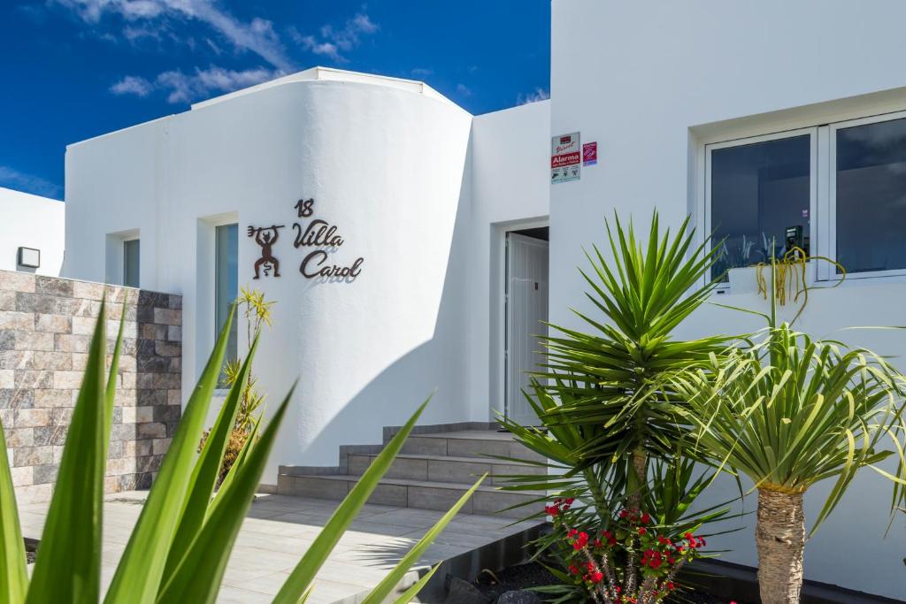 Ein weißes Gebäude mit einem Schild, auf dem Freude auf einem Kamel steht in der Unterkunft Villa Carol in Playa Blanca