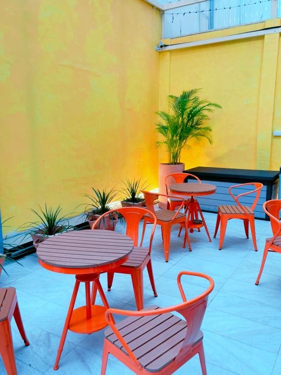 un patio con tavoli, sedie e parete gialla di 好客輕旅 a Donggang