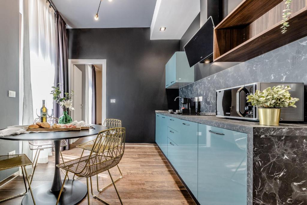 une cuisine avec des placards bleus et une table avec des chaises dans l'établissement Ugo Bassi Apartments, à Bologne
