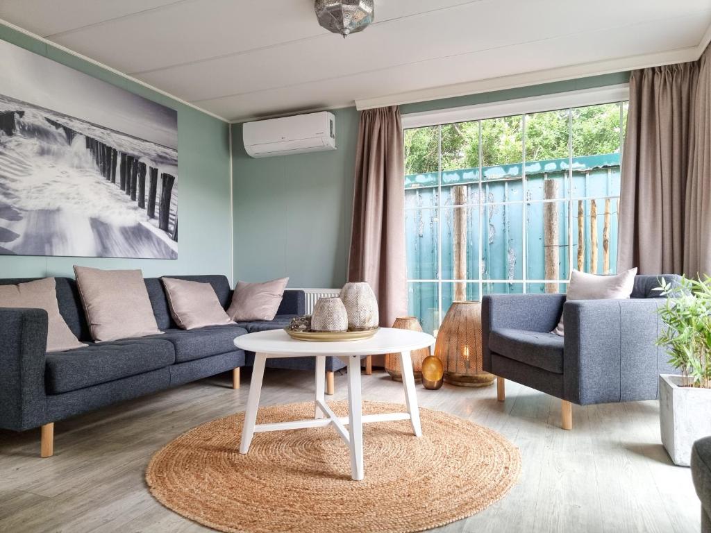 uma sala de estar com dois sofás e uma mesa em Chalet BG03 direct achter de duinen! em Biggekerke