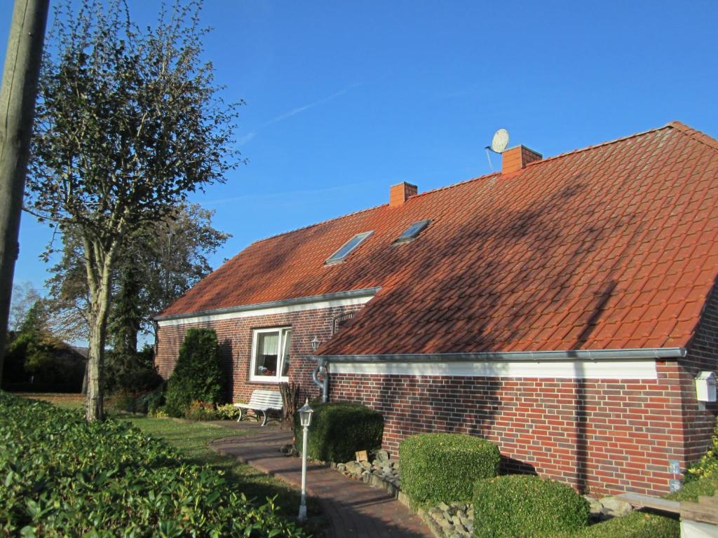 a red brick house with a red roof at Ferienwohnung Up Hobarg 35523 in Uplengen