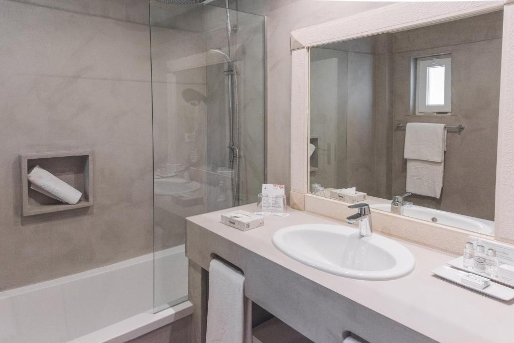 a bathroom with a sink and a glass shower at Costa d'Oiro Ambiance Village in Lagos