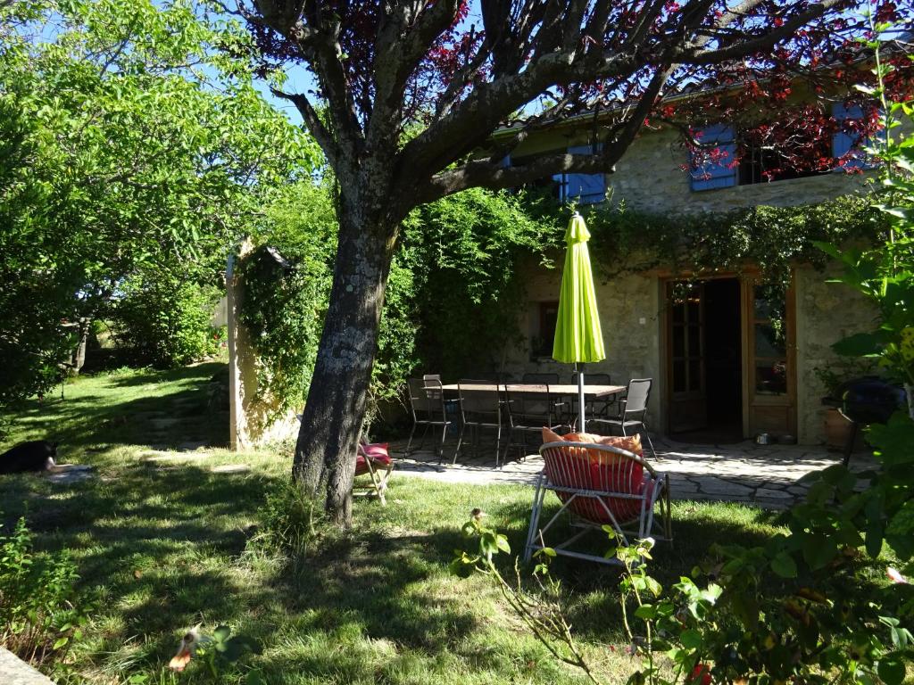 einen Tisch, einen gelben Regenschirm und einen Stuhl unter einem Baum in der Unterkunft Maison de charme à Saoû, avec beau jardin au calme in Saou