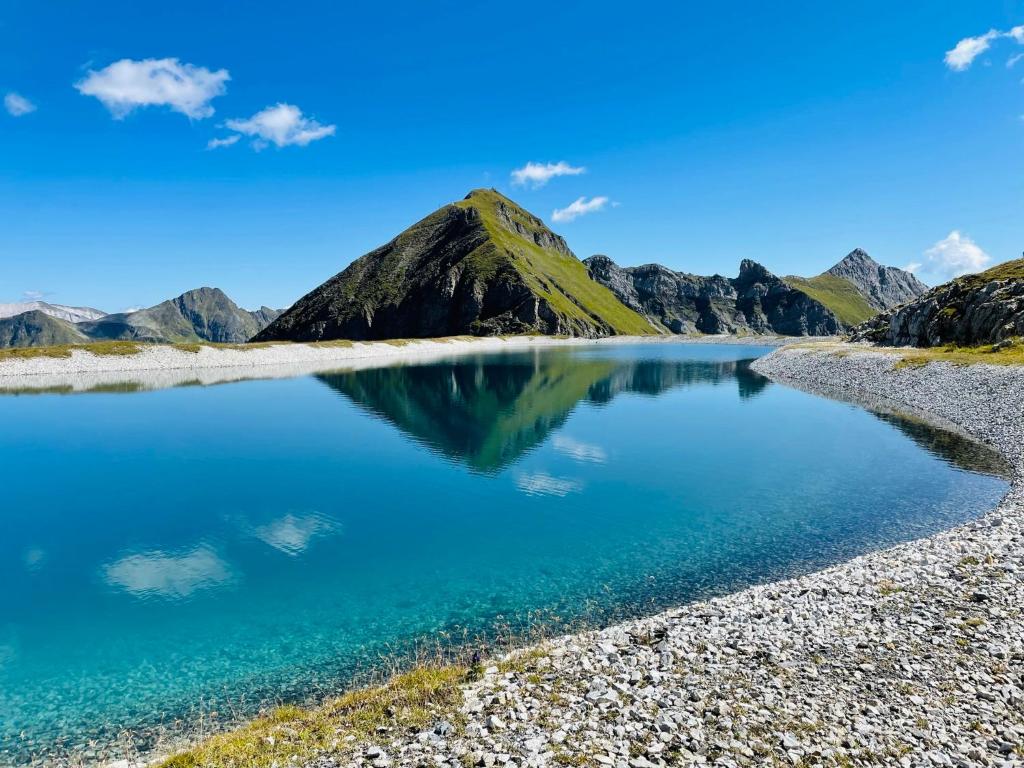a mountain reflecting in a lake in the mountains at Hotel Binggl in Obertauern