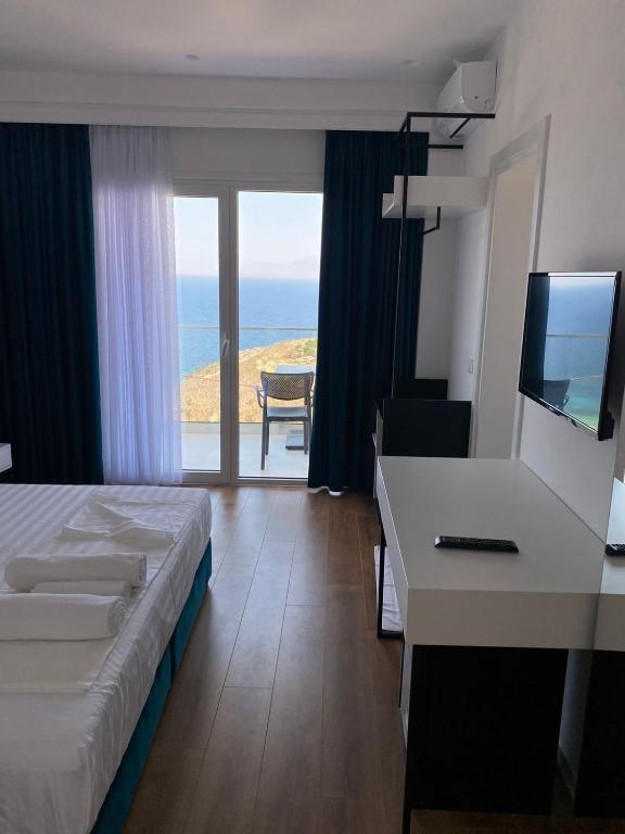 a hotel room with a bed and a desk with a television at SEA & LAKE VIEW VILLA in (( Kalive Gjoka ))