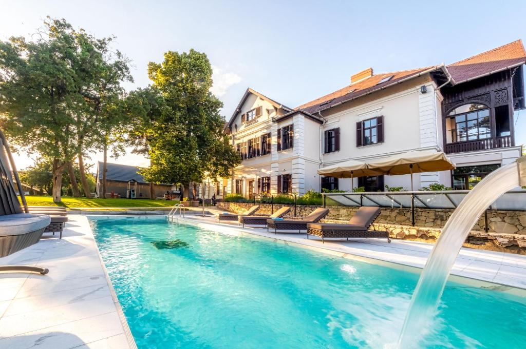 a swimming pool with a fountain in front of a house at Boutique Hotel Annuska in Balatonfüred