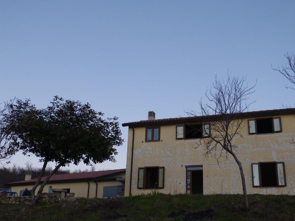 a building on a hill with a tree in front of it at IL Casale del Galantuomo in Castelsaraceno