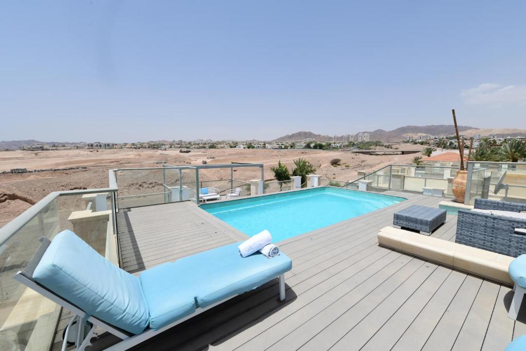 una terraza con un sillón azul y una piscina en Amdar Holiday Apartments with private pools, en Eilat