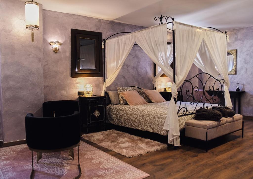 um quarto com uma cama de dossel e uma cadeira em Riad Medina Mudéjar Cádiz em Chiclana de la Frontera