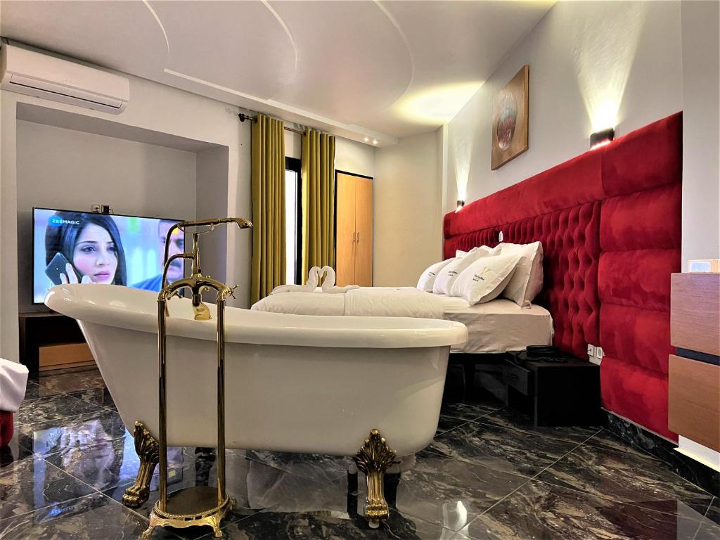 a bathroom with a tub and a bed and a tv at Hôtel Vendôme Douala in Douala