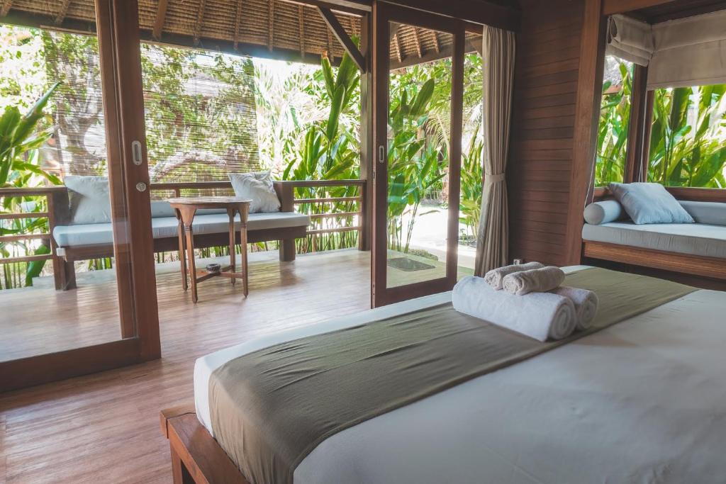 1 dormitorio con 1 cama grande en una habitación con ventanas en Guava Garden, en Gili Trawangan