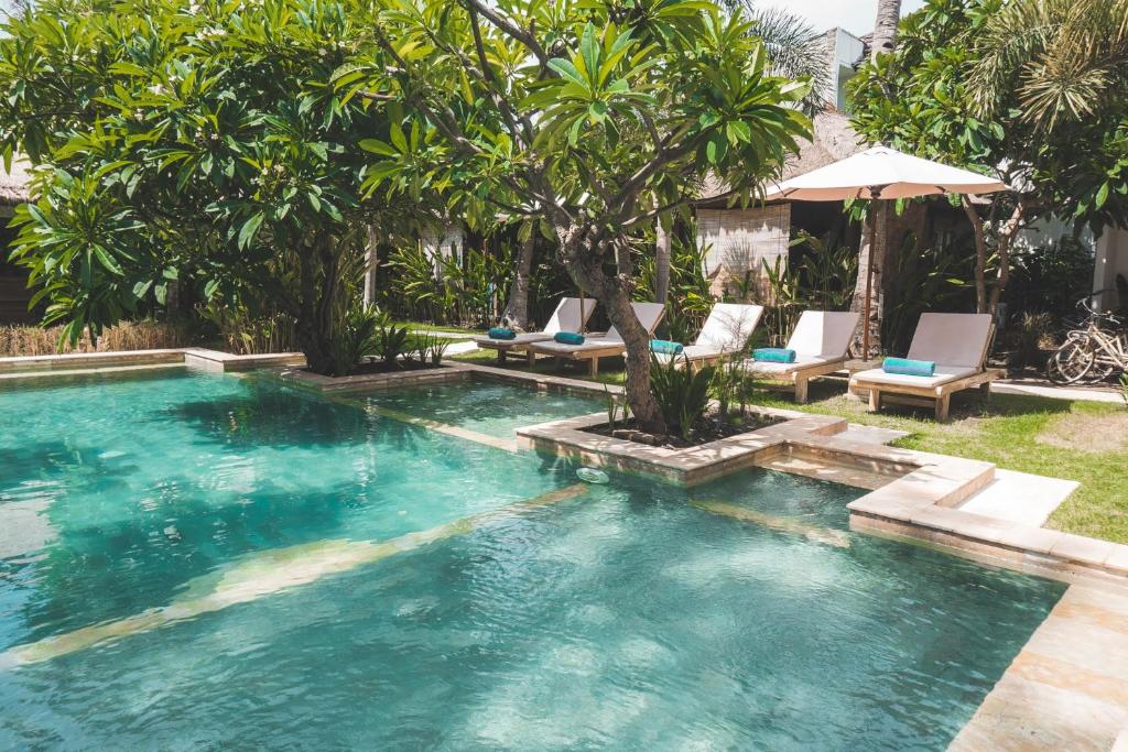 a swimming pool with lounge chairs in a backyard at Guava Garden in Gili Trawangan