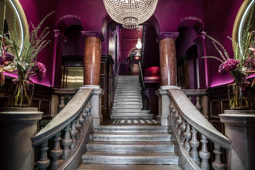 a spiral staircase in a purple building with a chandelier at Hotel Josefine in Vienna