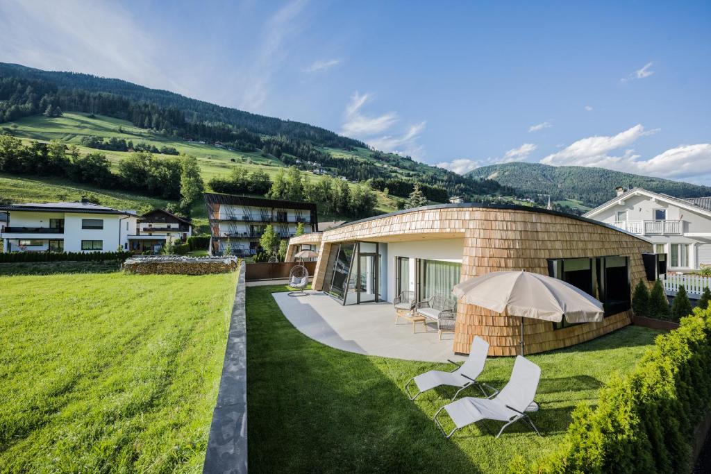 a building with two white chairs in the grass at Chalets Dolomit Royal in Sillian