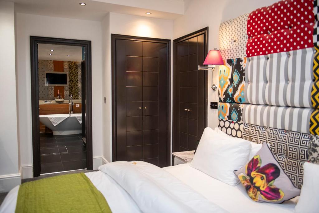 1 Schlafzimmer mit einem weißen Bett und einem Badezimmer in der Unterkunft The Exhibitionist Hotel in London