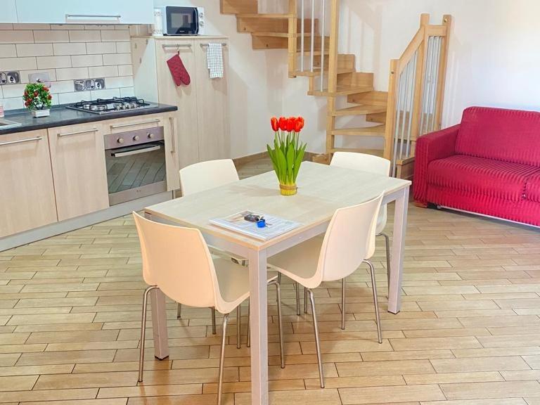 a kitchen with a table with white chairs and a red couch at Country Love Dragona House tra mare e città in Acilia
