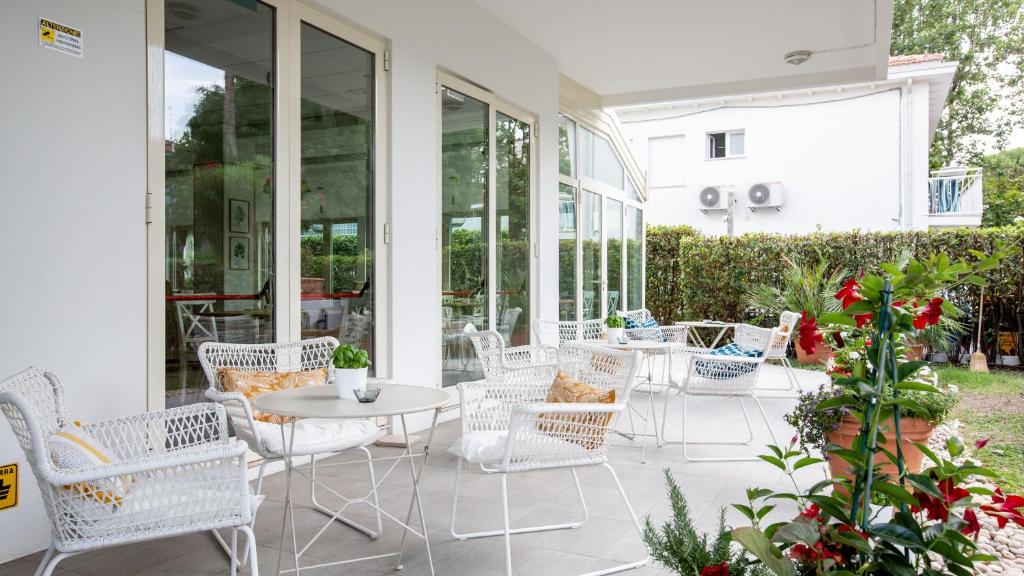 a patio with white chairs and a table at BeYou Hotel Villa Rosa in Riccione