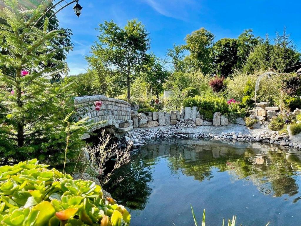 a stone bridge over a pond in a garden at Apartament Nad Potokiem in Jelenia Góra