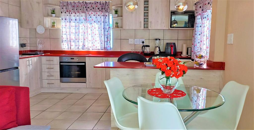 una cocina con una mesa de cristal con flores. en Arlogenix, en Durbanville